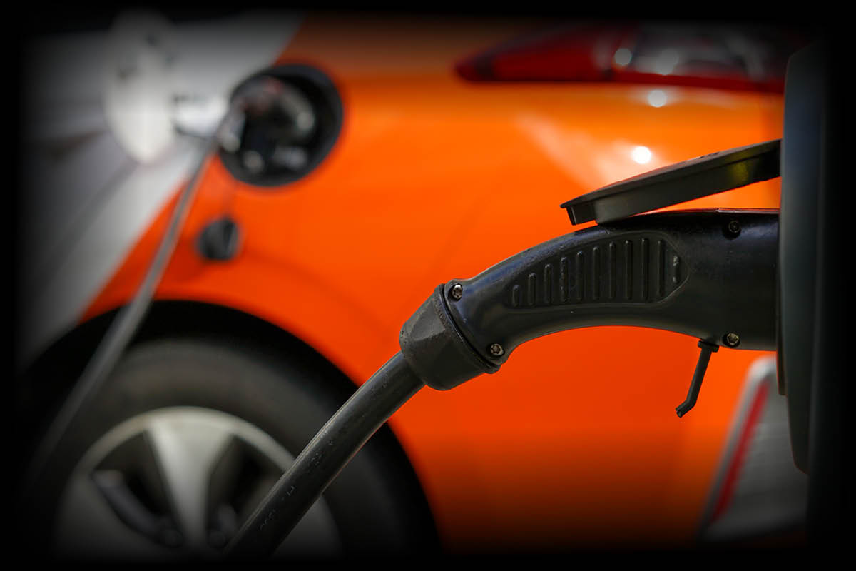 Elektroauto, das gerade an einer Ladestation aufgeladen wird. Im Vordergrund sieht man den Ladestecker, der mit dem Fahrzeug verbunden ist.