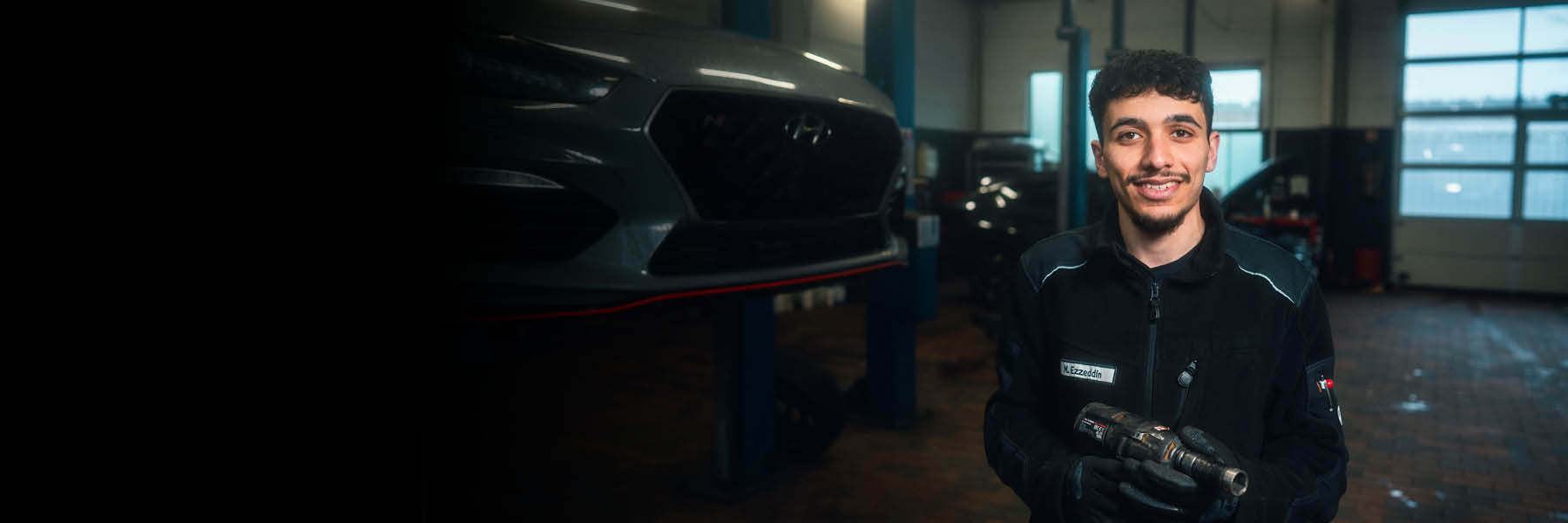 In einer Autowerkstatt steht eine Person in Arbeit