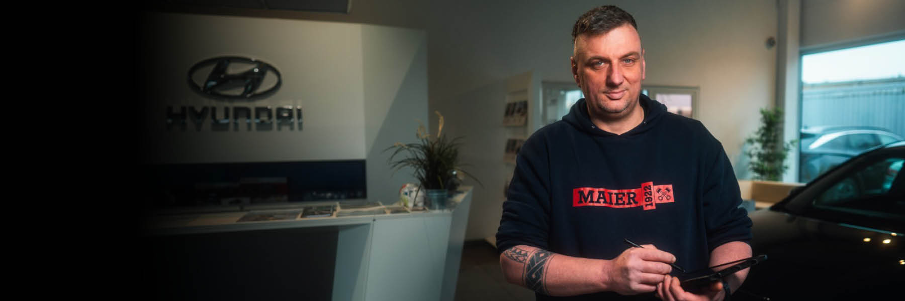 Eine Person steht in einem Hyundai-Autohaus an einem Tresen und hält ein Tablet in der Hand.