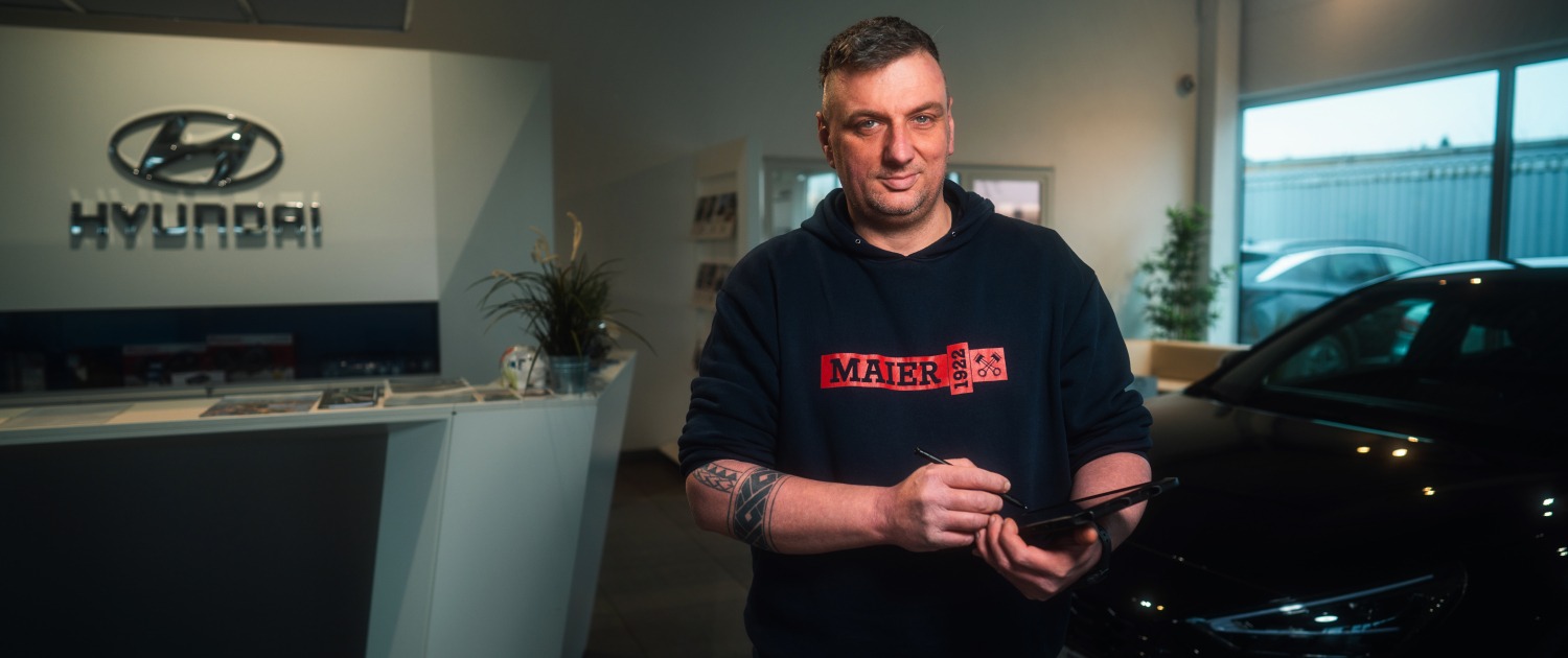 Eine Person steht in einem Hyundai-Autohaus an einem Tresen und hält ein Tablet in der Hand.