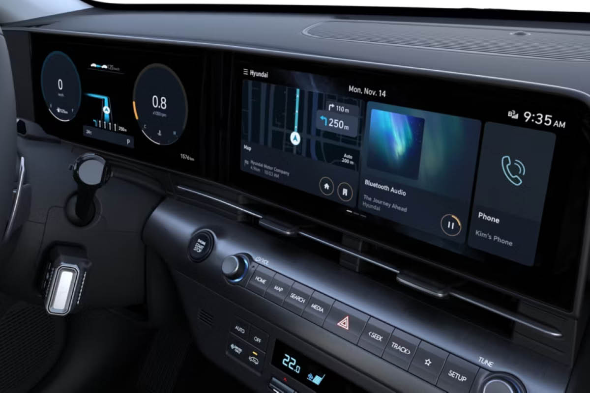 Nahaufnahme des Cockpits eines modernen Autos: zwei breite Digitaldisplays mit Tacho, Navigation, Musik und Telefonanzeige, darunter Tastenleiste und Klimabedieneinheit mit Start/Stopp-Knopf.